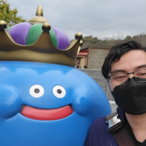Keita Moore in front of a Dragon Quest statue